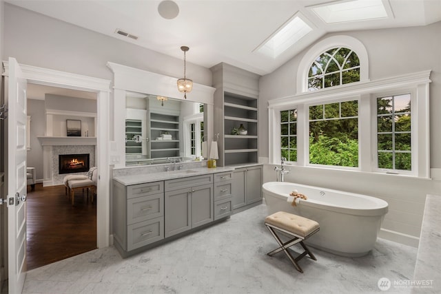 bathroom with vanity, a tub, plenty of natural light, and vaulted ceiling with skylight