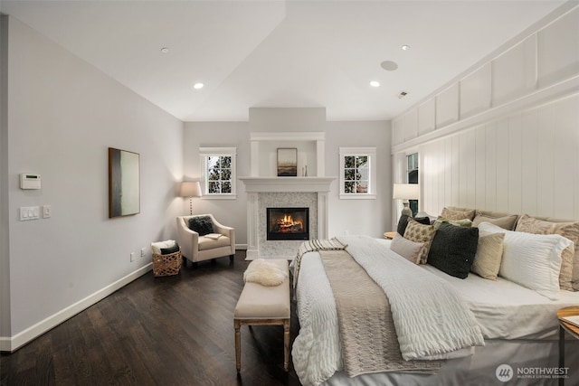 bedroom with a tiled fireplace, lofted ceiling, and dark wood-type flooring