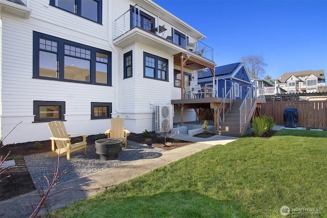 back of property with ac unit, a lawn, a fire pit, a balcony, and a wooden deck