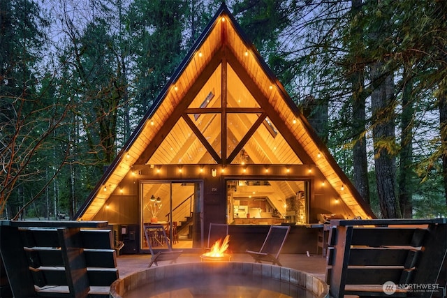 rear view of property with a wooden deck and an outdoor fire pit