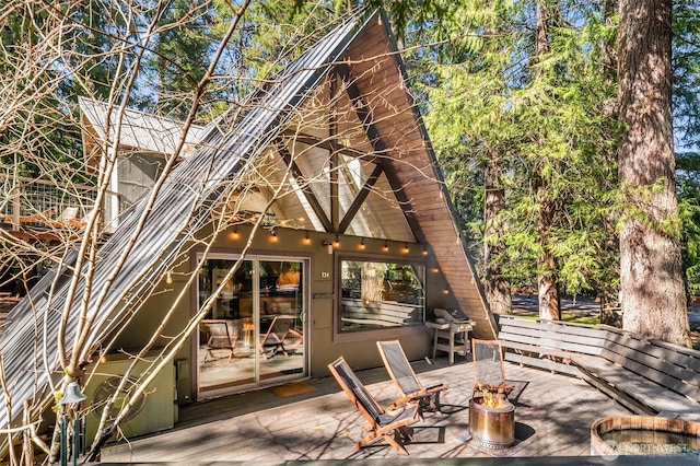 wooden deck with area for grilling, a fire pit, and a patio