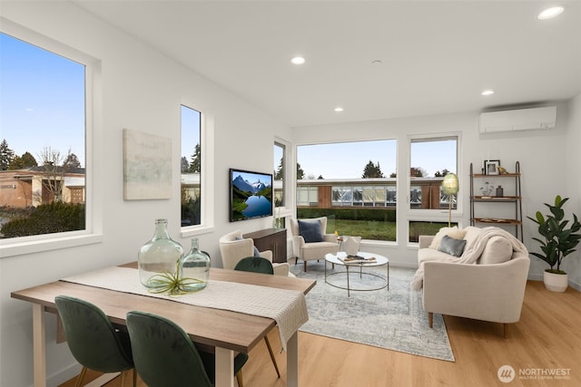 living room featuring plenty of natural light, light wood-type flooring, and an AC wall unit