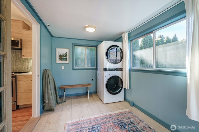 clothes washing area with stacked washer and clothes dryer and light wood-type flooring