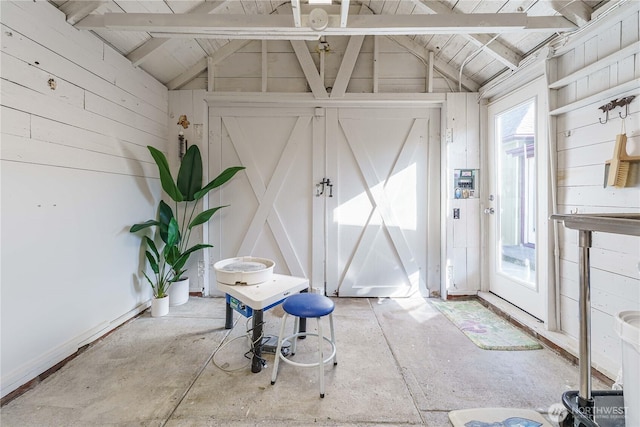 interior space with vaulted ceiling with beams and wooden walls