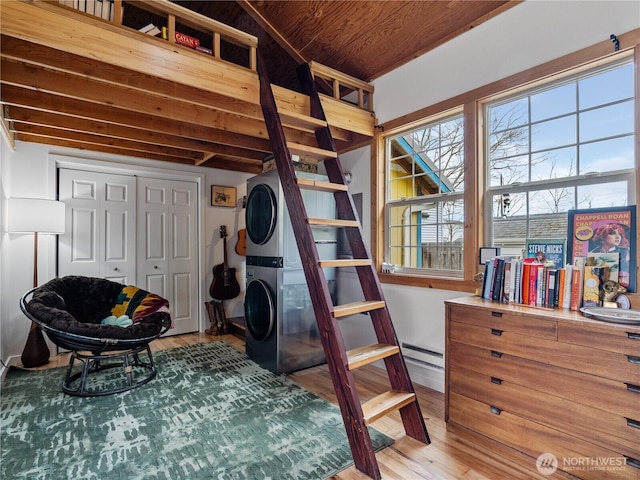 bedroom with wood ceiling, stacked washer and clothes dryer, hardwood / wood-style floors, and a closet