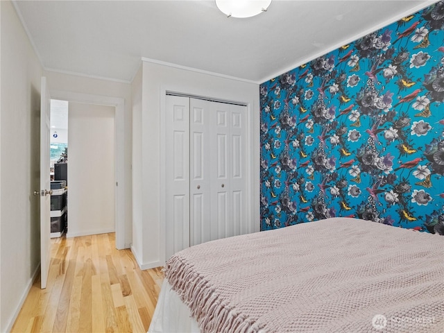 bedroom featuring hardwood / wood-style flooring, ornamental molding, and a closet