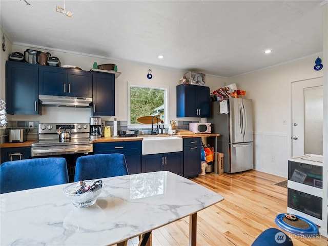 kitchen with sink, crown molding, light hardwood / wood-style flooring, blue cabinetry, and stainless steel appliances