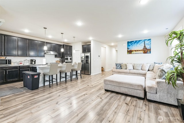 living room featuring light wood-type flooring, baseboards, and recessed lighting