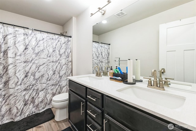 bathroom with visible vents, a sink, toilet, and double vanity