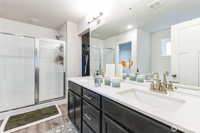 bathroom featuring visible vents, a walk in closet, a sink, and wood finished floors