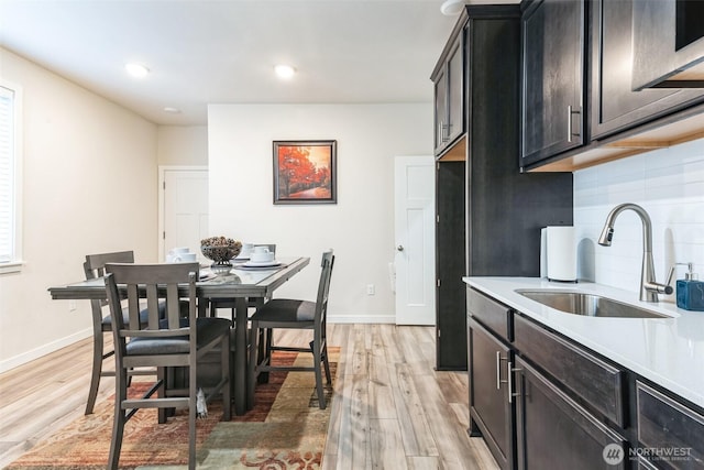 kitchen with light countertops, tasteful backsplash, a sink, and light wood-style floors