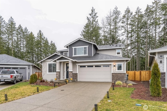 craftsman-style home with concrete driveway, stone siding, an attached garage, fence, and a front lawn