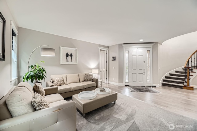 living room featuring stairs, baseboards, wood finished floors, and recessed lighting