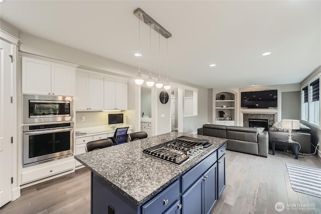 kitchen with white cabinets, a kitchen island, hanging light fixtures, stainless steel appliances, and blue cabinetry