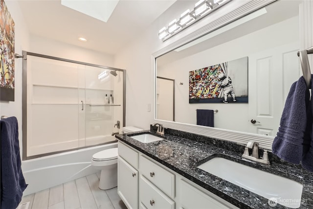 bathroom with toilet, double vanity, combined bath / shower with glass door, and a sink