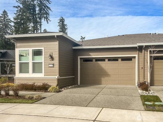 view of front of home with driveway, roof with shingles, and an attached garage