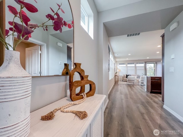 hallway with baseboards, wood finished floors, visible vents, and recessed lighting