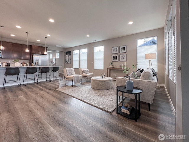 living room featuring dark wood-type flooring, recessed lighting, and a healthy amount of sunlight