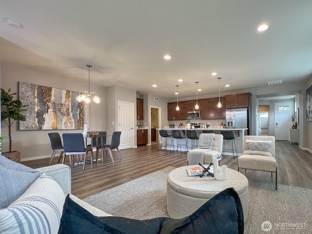 living room with recessed lighting, visible vents, baseboards, and wood finished floors