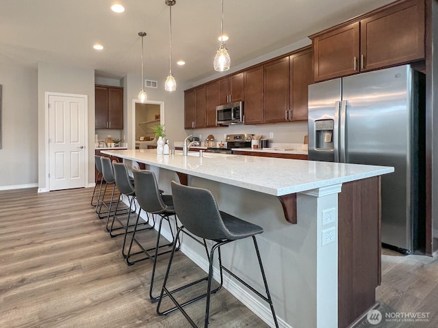 kitchen with a breakfast bar area, recessed lighting, visible vents, light wood-style flooring, and appliances with stainless steel finishes