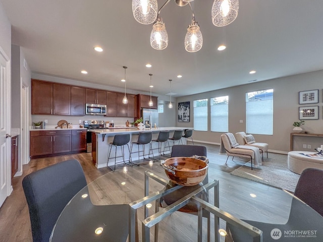 dining room featuring baseboards, wood finished floors, and recessed lighting