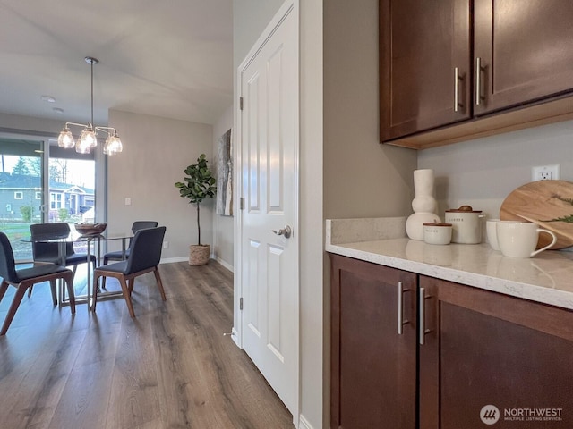 dining area with a chandelier, dark wood finished floors, and baseboards