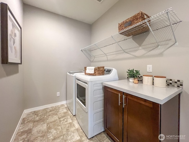 clothes washing area featuring baseboards and washer and clothes dryer