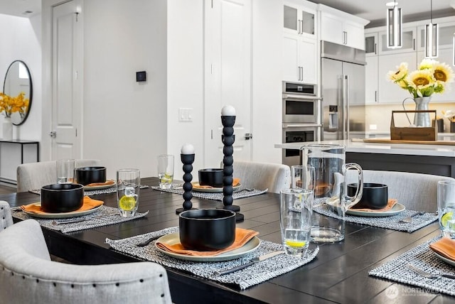 kitchen with white cabinets, appliances with stainless steel finishes, and decorative light fixtures