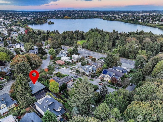 aerial view at dusk featuring a residential view and a water view