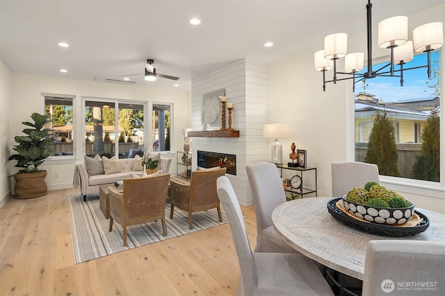 dining room featuring ceiling fan with notable chandelier and light hardwood / wood-style floors