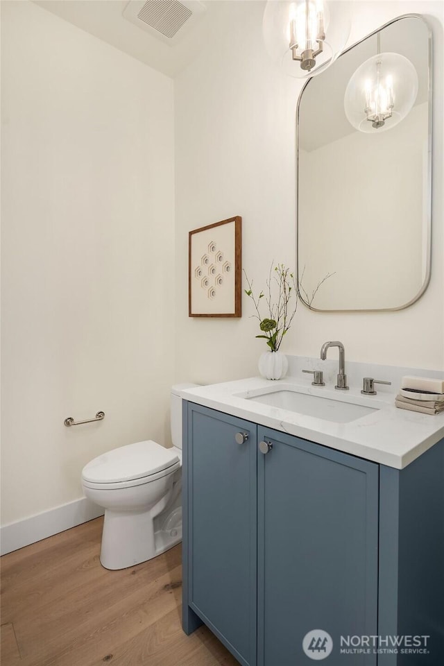 bathroom featuring vanity, a notable chandelier, hardwood / wood-style flooring, and toilet