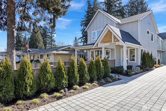 view of front of house with board and batten siding, fence, and a shingled roof