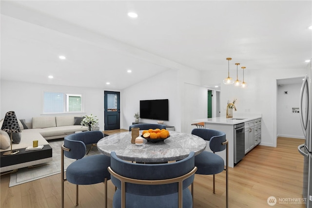 living room featuring sink, lofted ceiling, and light wood-type flooring