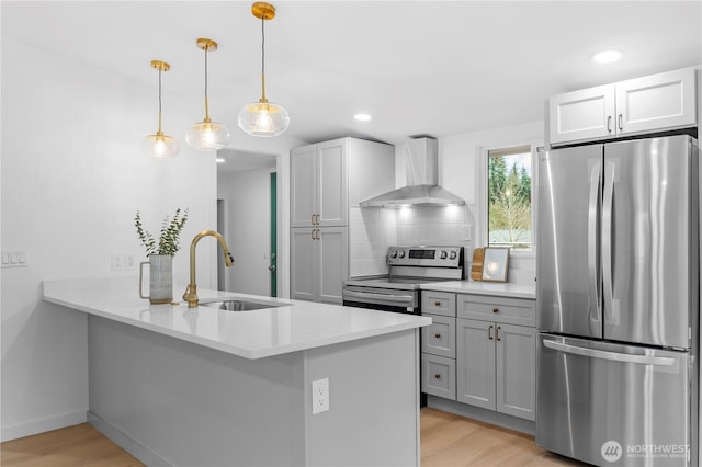 kitchen featuring appliances with stainless steel finishes, sink, wall chimney exhaust hood, kitchen peninsula, and hanging light fixtures