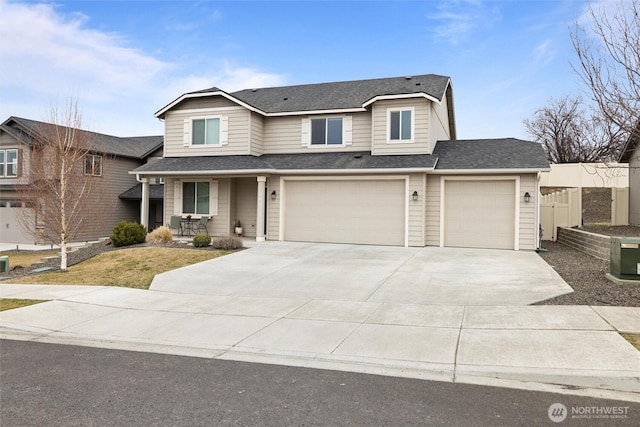 traditional-style home featuring a shingled roof, covered porch, fence, and concrete driveway