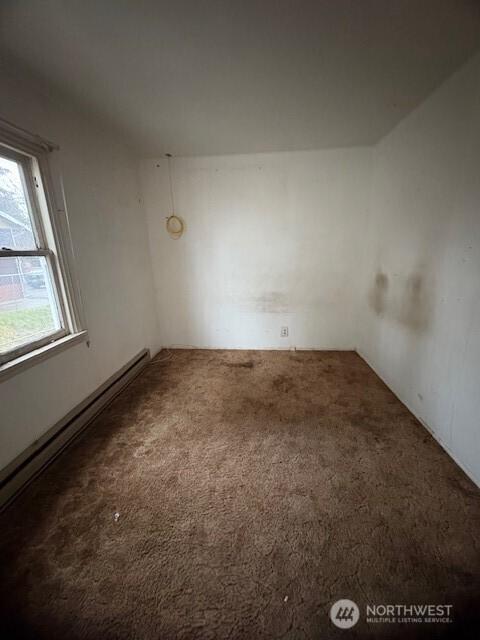 spare room featuring a baseboard heating unit and carpet flooring