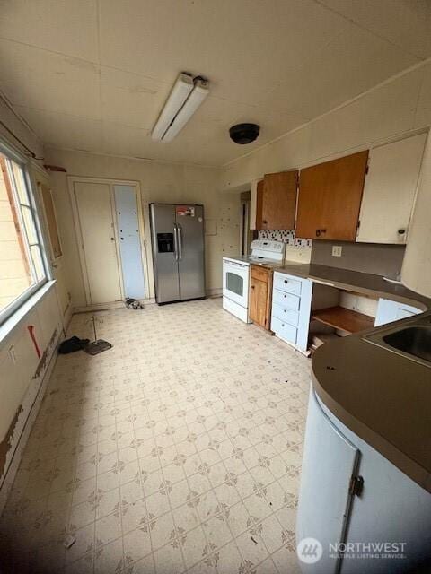 kitchen featuring stainless steel fridge with ice dispenser and white range with electric stovetop