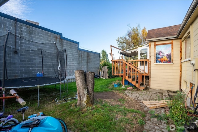 view of yard with stairs, a trampoline, and a deck