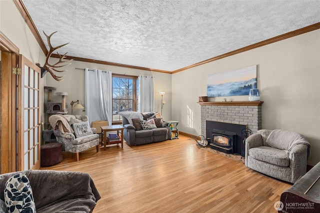 living room with crown molding, a brick fireplace, a textured ceiling, and light wood-type flooring