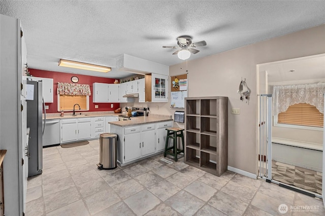 kitchen with sink, a textured ceiling, appliances with stainless steel finishes, ceiling fan, and white cabinets