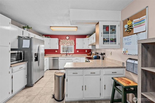 kitchen with sink, appliances with stainless steel finishes, a textured ceiling, white cabinets, and kitchen peninsula