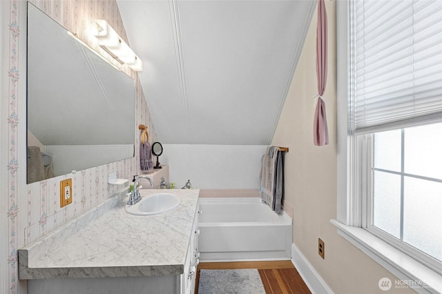 bathroom with vanity, a tub, wood-type flooring, and lofted ceiling