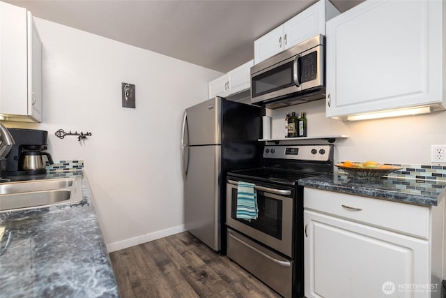 kitchen with sink, white cabinets, dark stone counters, stainless steel appliances, and dark wood-type flooring