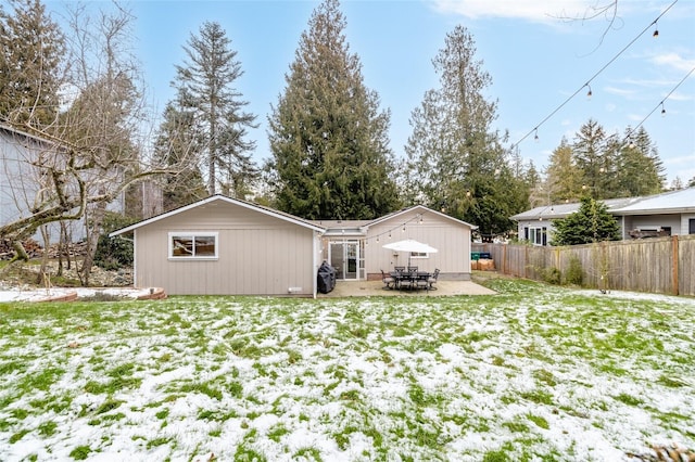 snow covered rear of property featuring a yard and a patio area