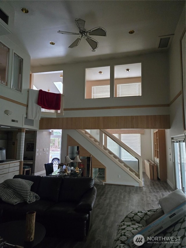 living room featuring ceiling fan, hardwood / wood-style floors, and a high ceiling