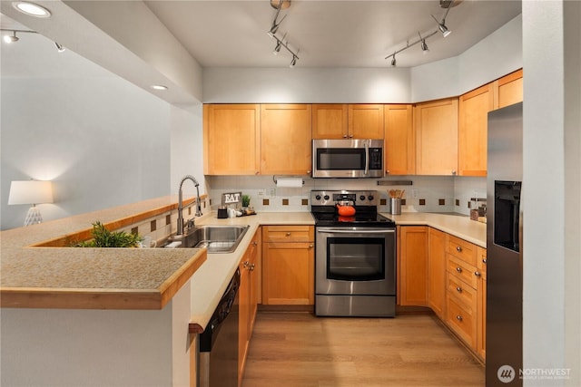 kitchen featuring tasteful backsplash, sink, stainless steel appliances, and kitchen peninsula