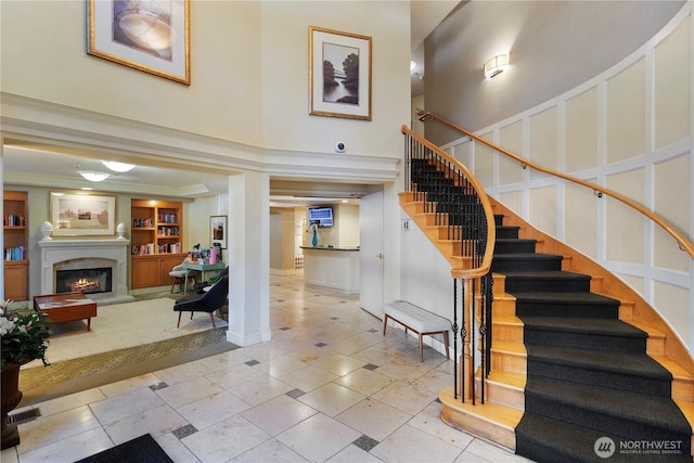 staircase with a high ceiling, ornamental molding, tile patterned floors, and built in shelves