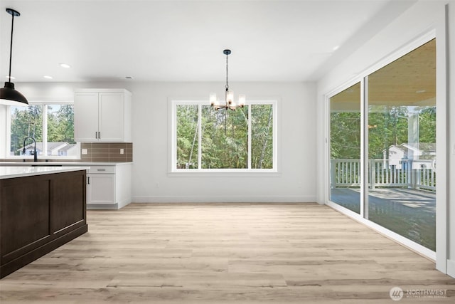 kitchen featuring white cabinetry, sink, pendant lighting, and backsplash