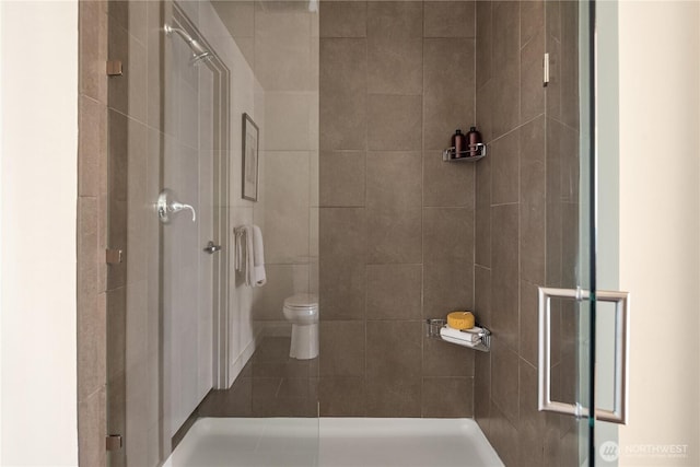 bathroom with a shower with door and toilet