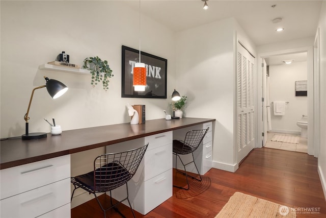 office area with dark wood-type flooring and built in desk